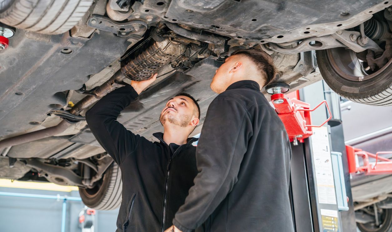 Mechanics inspecting car exhaust system in auto repair shop