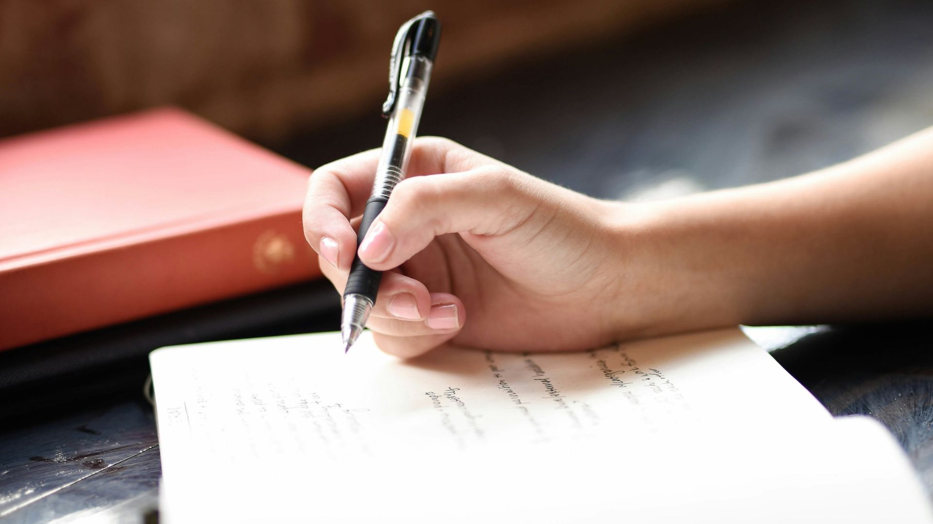 a person writing on a piece of paper with a pen