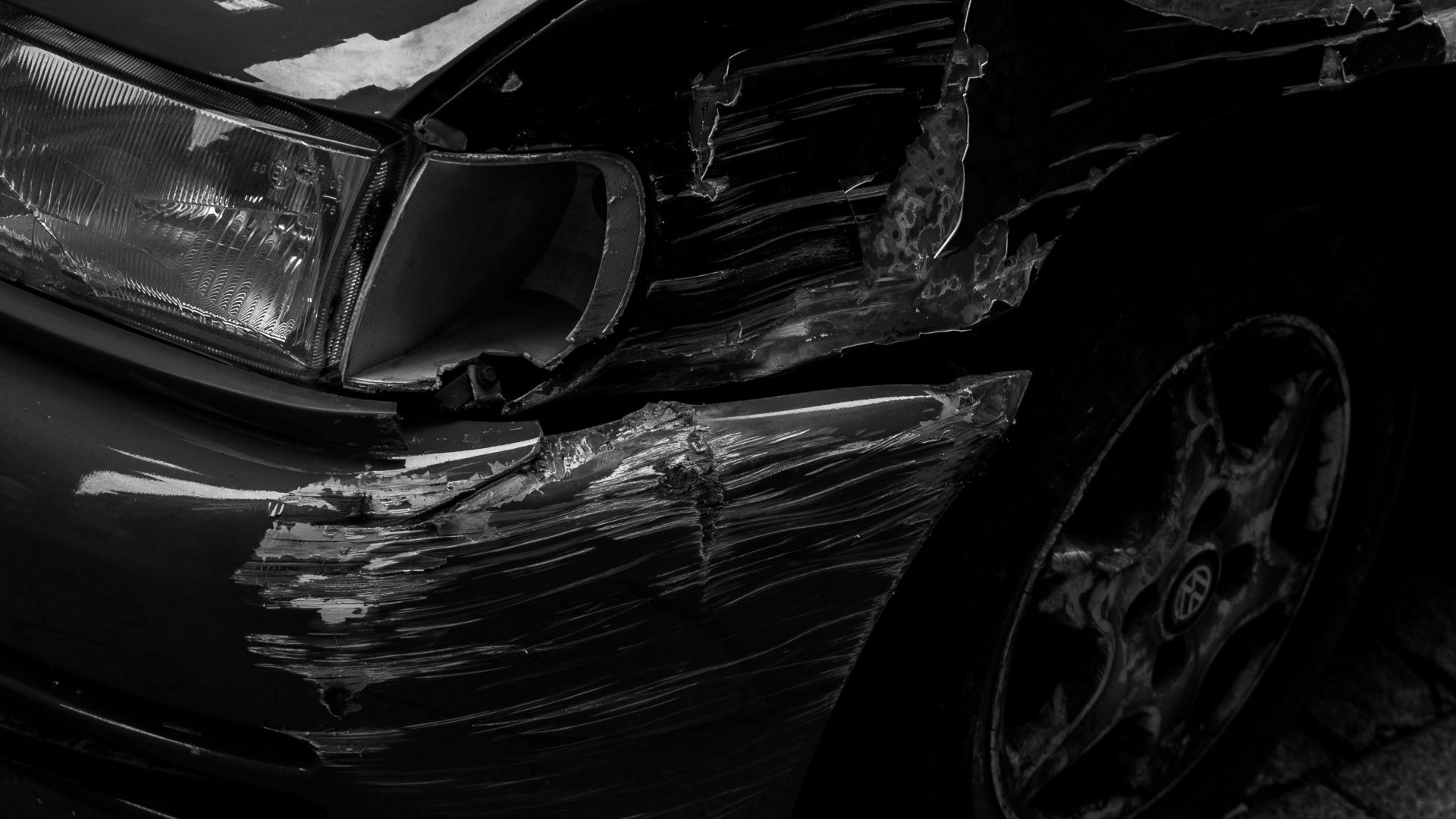 Artistic black and white image of a scratched car fender parked on a cobblestone sidewalk in Porto.