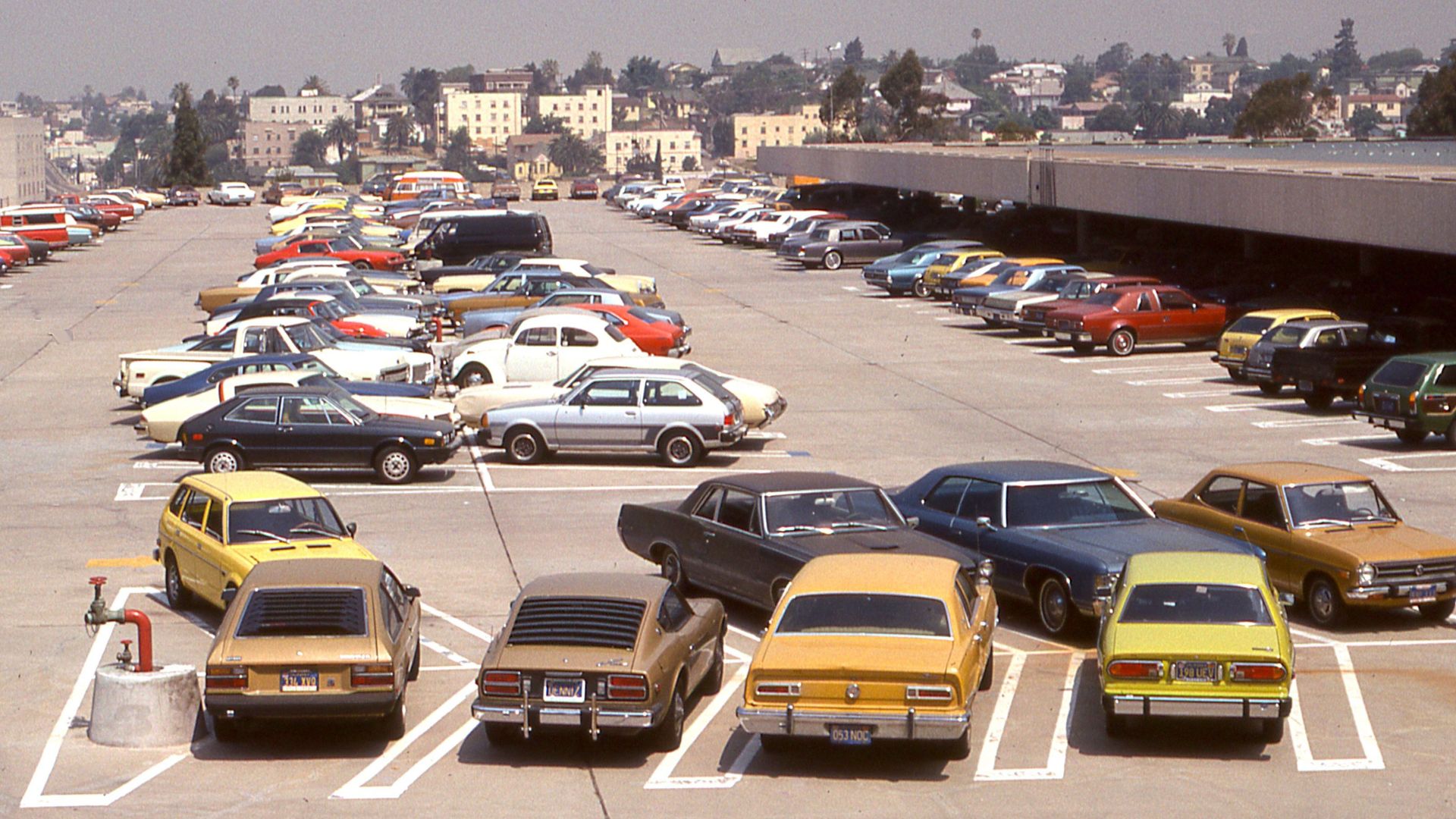 A high angle view of a parking lot filled with classic vintage cars on a sunny day.