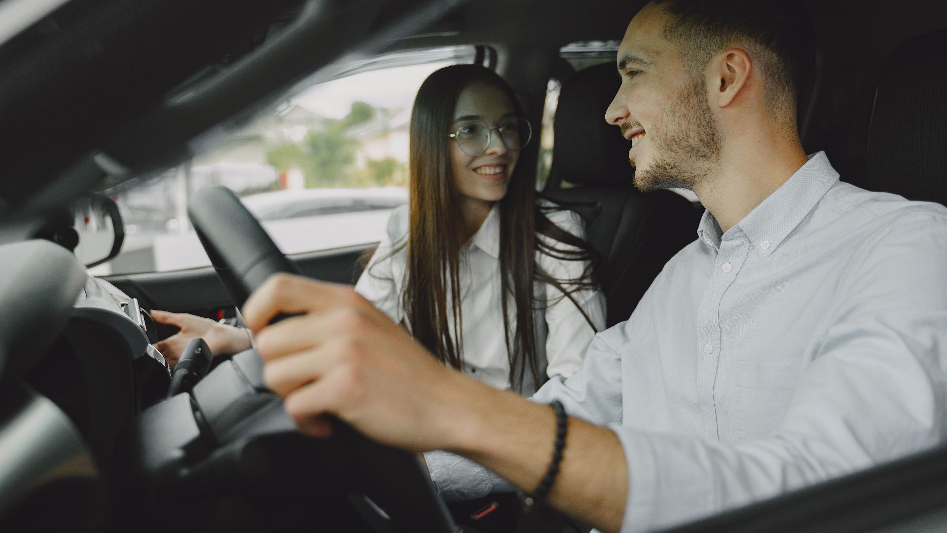 A smiling couple driving together in a car, enjoying their time on the road.