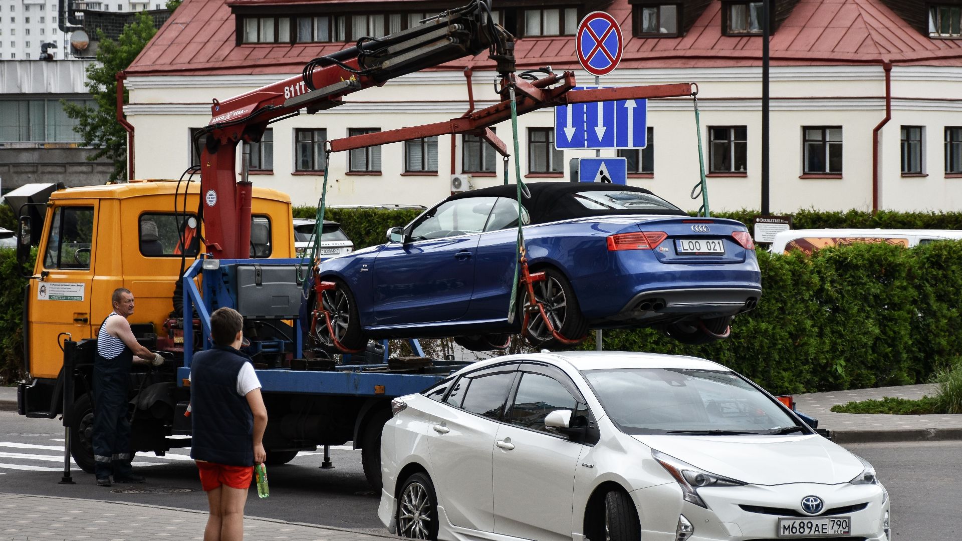 Towing a blue Audi convertible in a bustling city street.