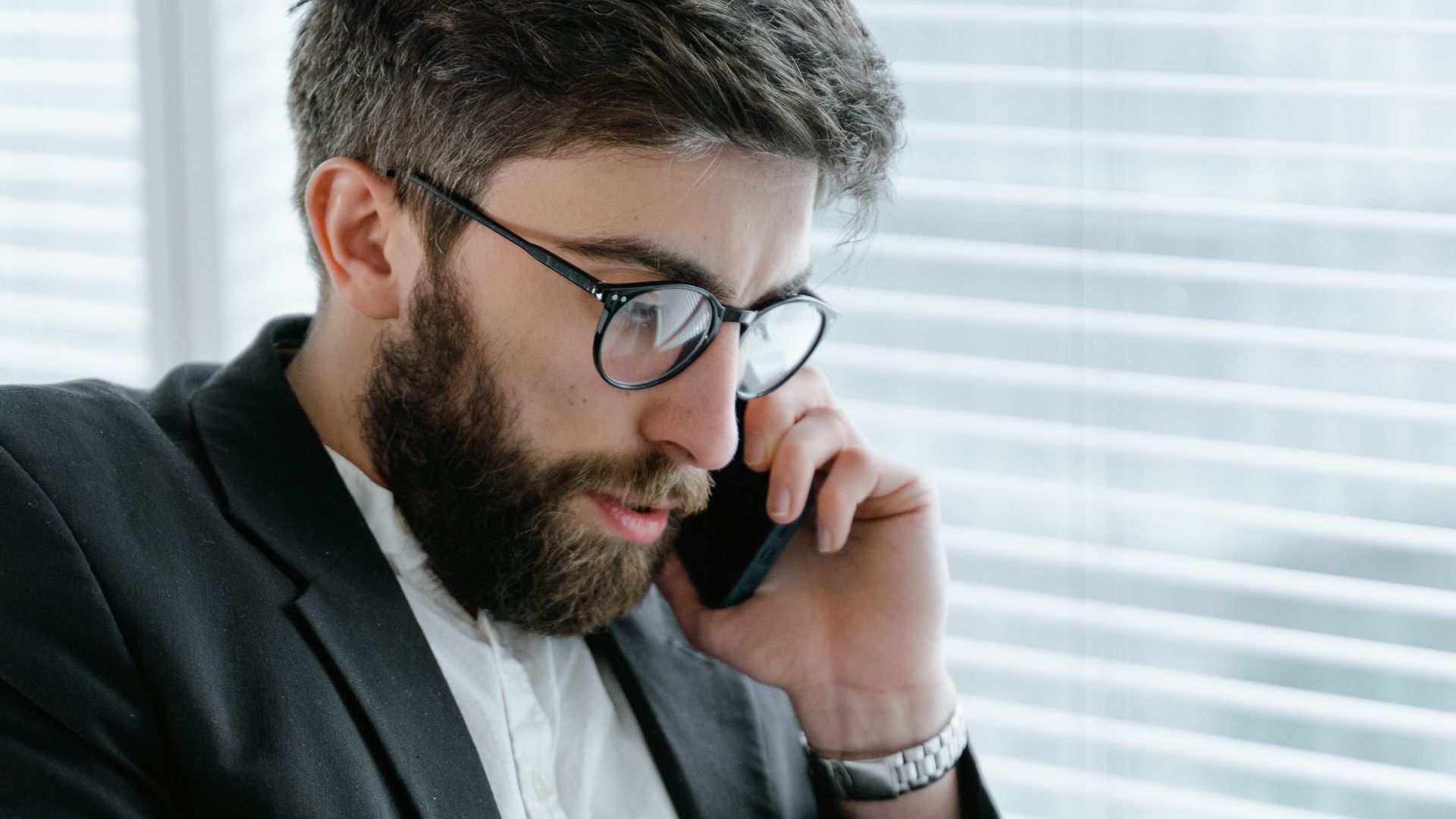 Focused businessman in office, analyzing documents while on a phone call.