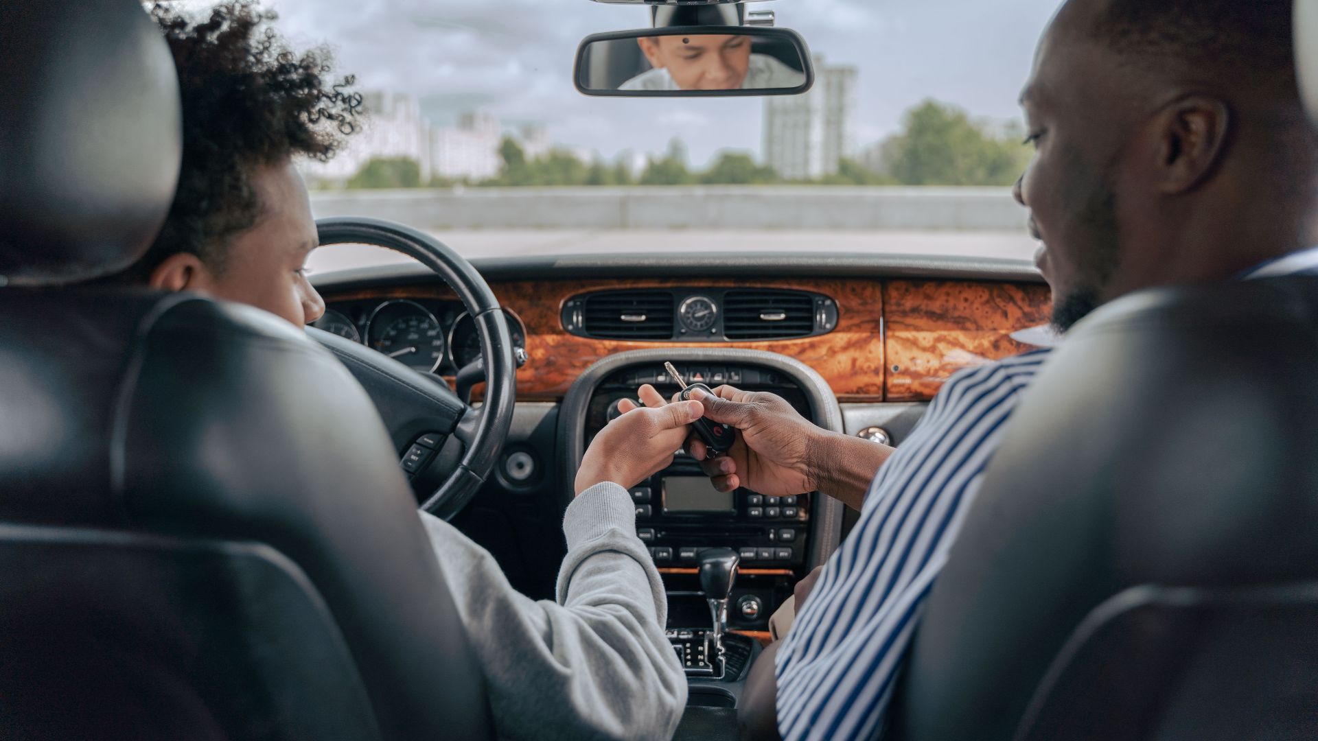 Father and teenage son inside car learning to drive, fostering bonding and guidance.