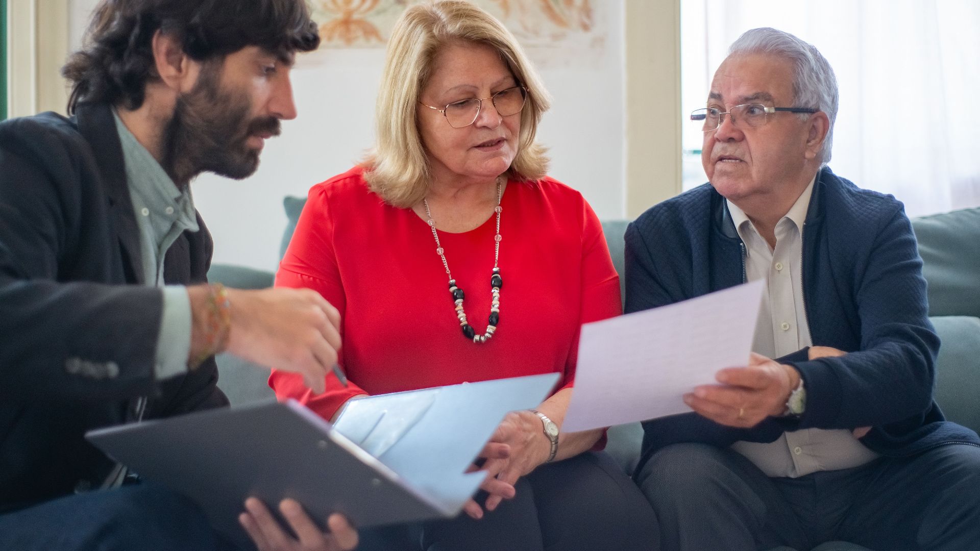 Senior couple consulting with a professional advisor, discussing documents indoors.