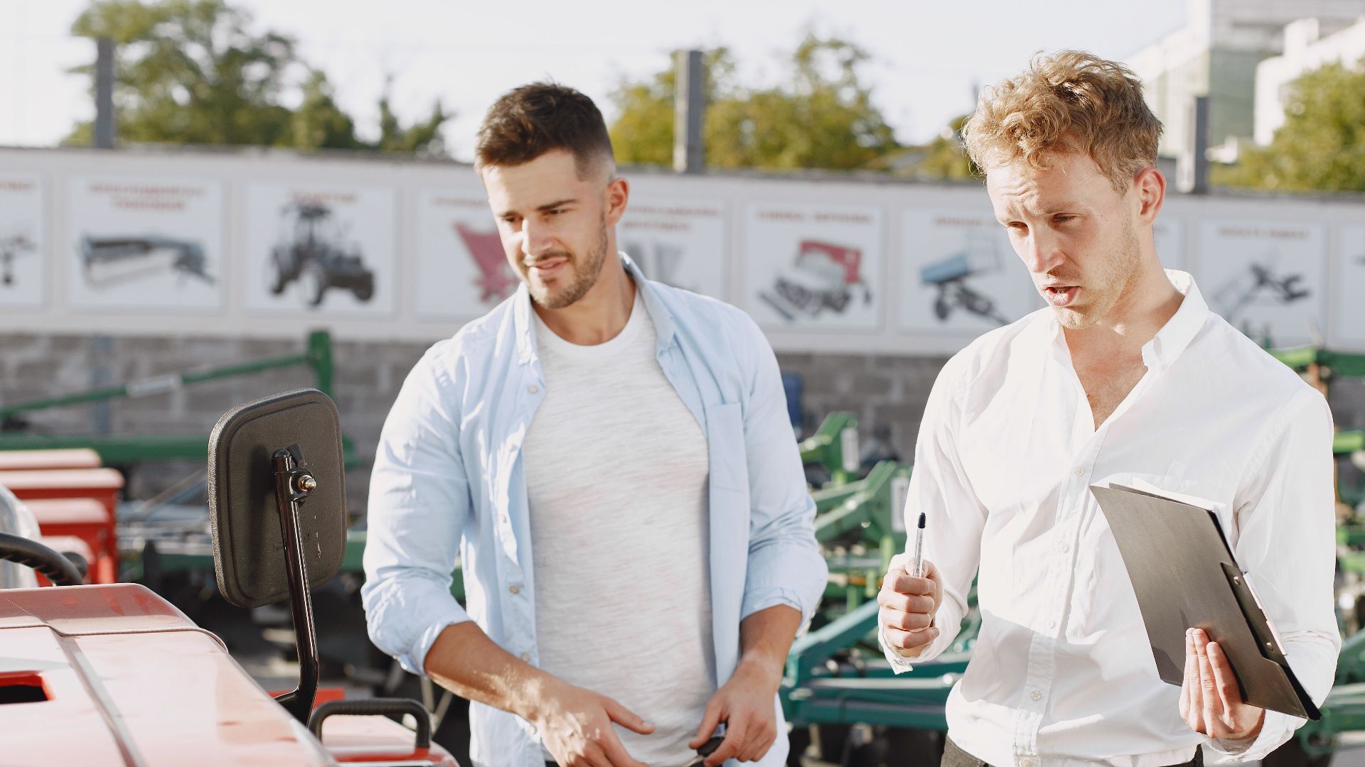 Two men engaging in a discussion about a tractor sale at an outdoor dealership.