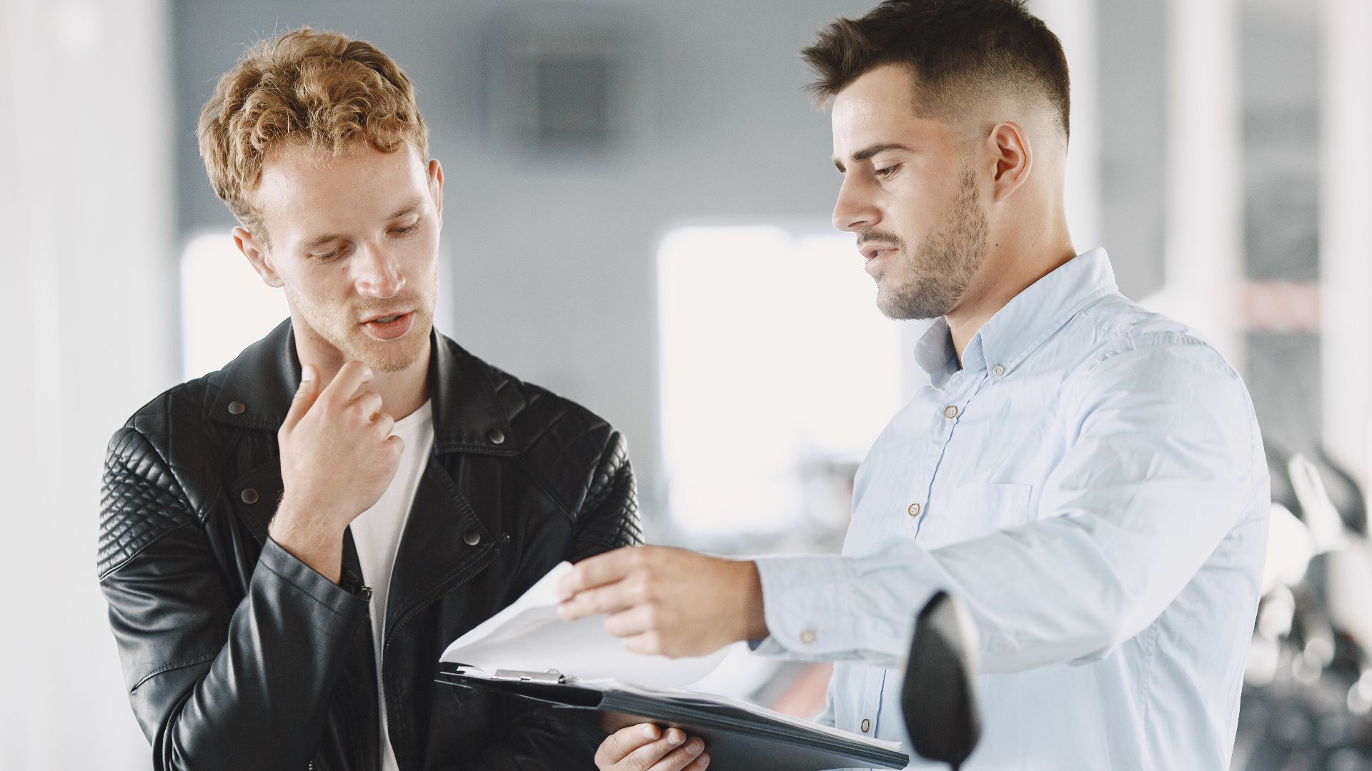 Two adults discussing purchasing options at a motorcycle dealership.