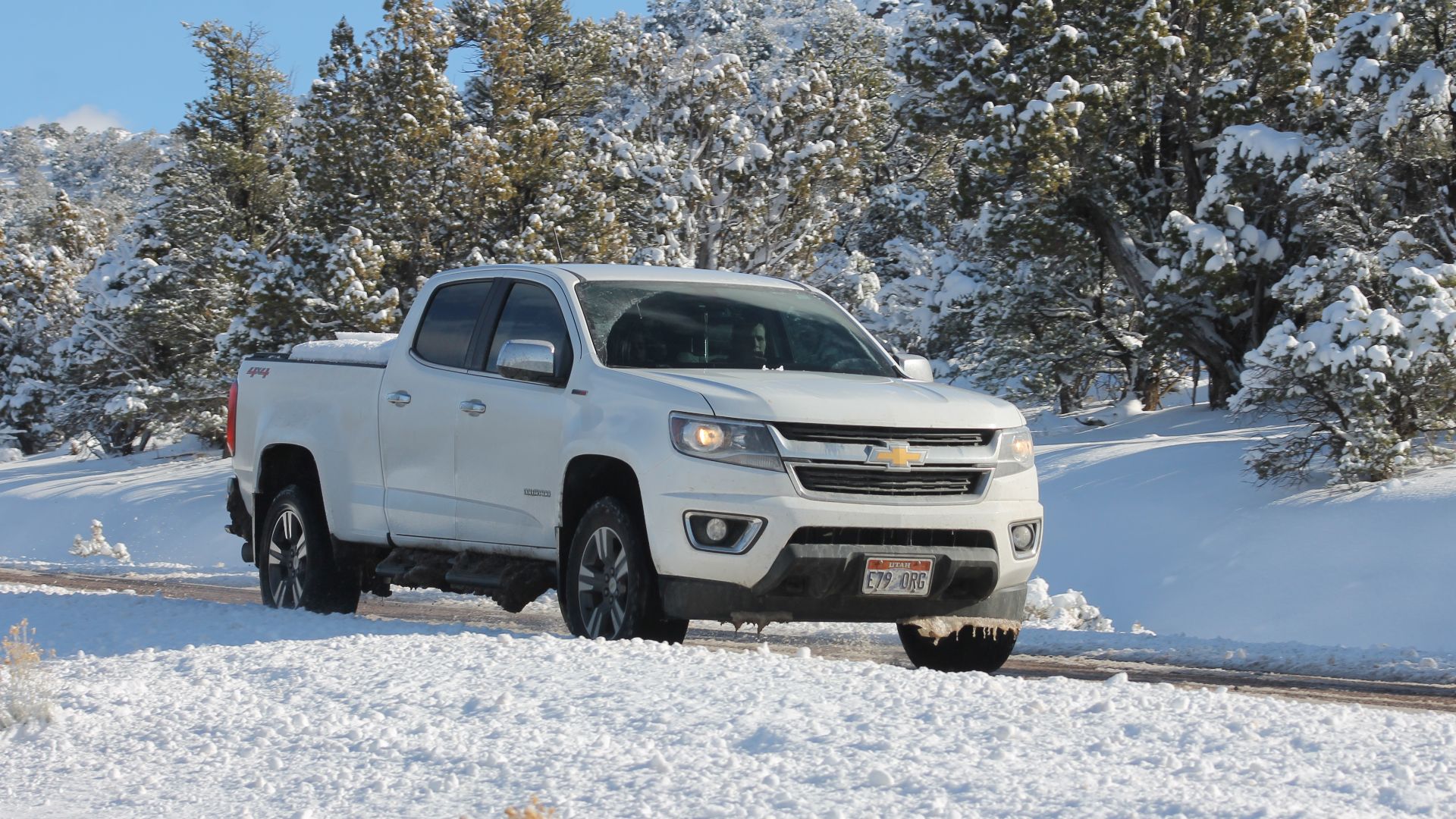 A white, snow coverd Second Generation Chevrolet Colorado driving on a snowy mountain in southern Utah.