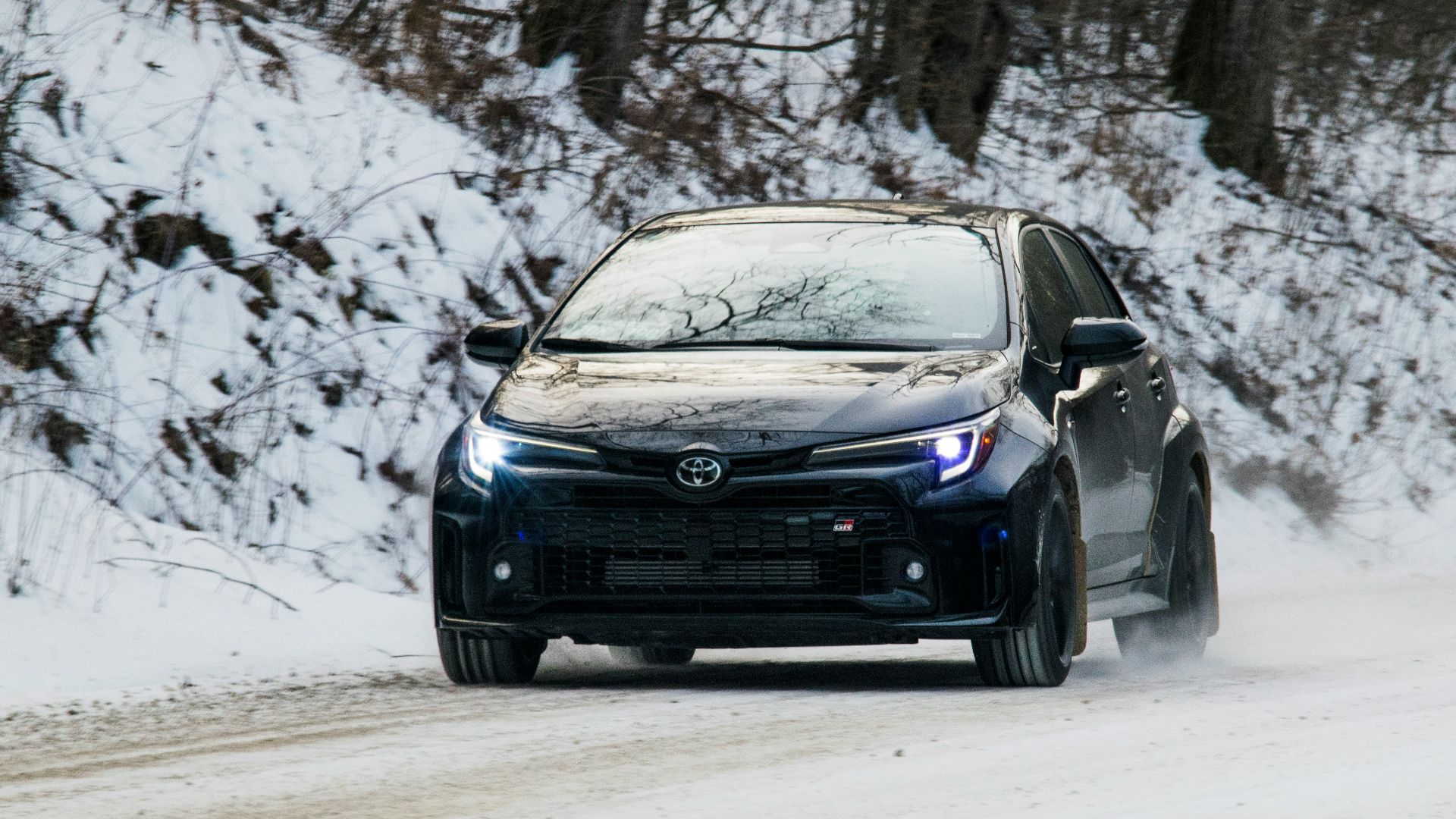 A black car drives through snowy conditions