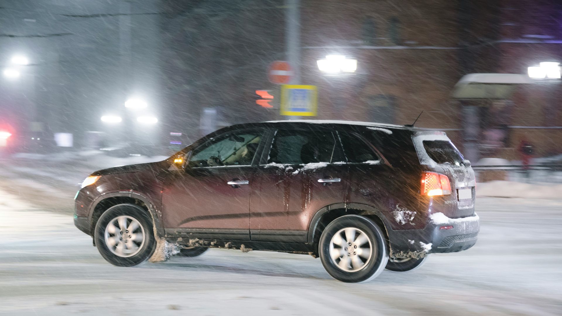 a car driving down a snowy street at night
