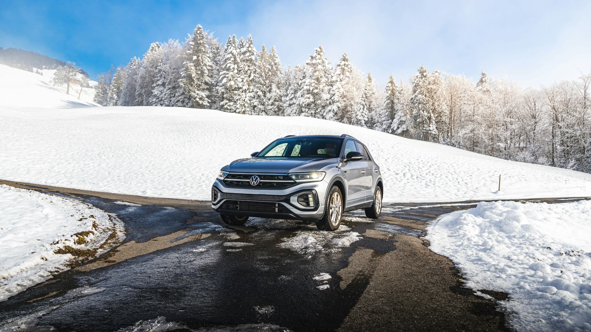 a car driving on a snowy road in the mountains