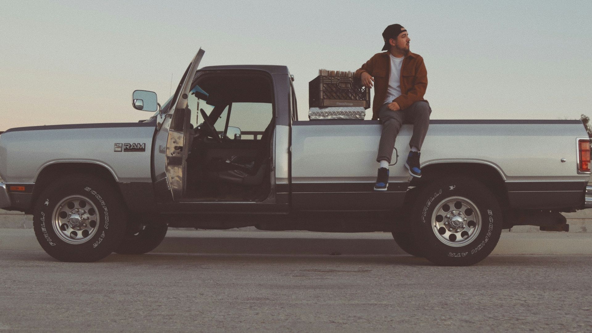 man in white t-shirt and black pants standing beside white crew cab pickup truck