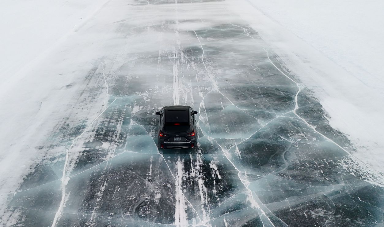 Car driving on a frozen icy road in Canada. Captured from above, showcasing winter's beauty.