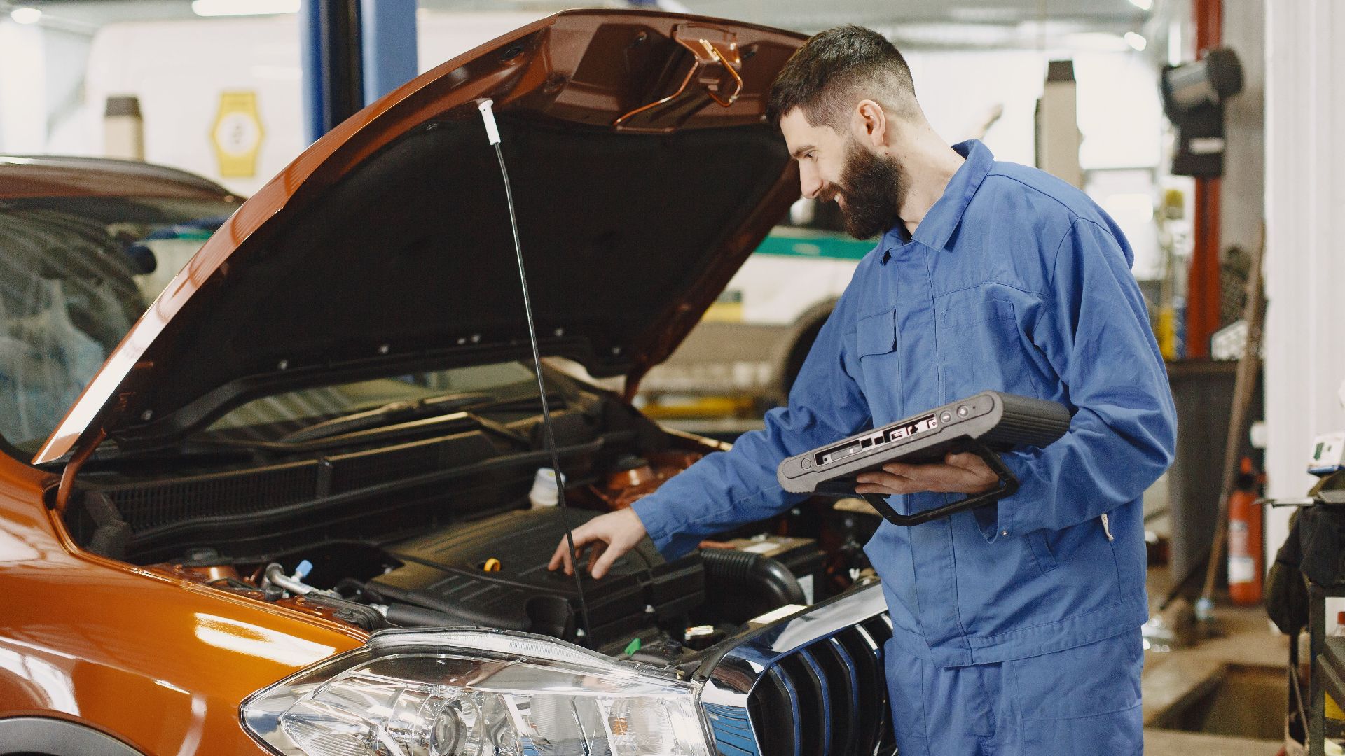 Skilled mechanic working on car engine diagnostics in a modern garage.