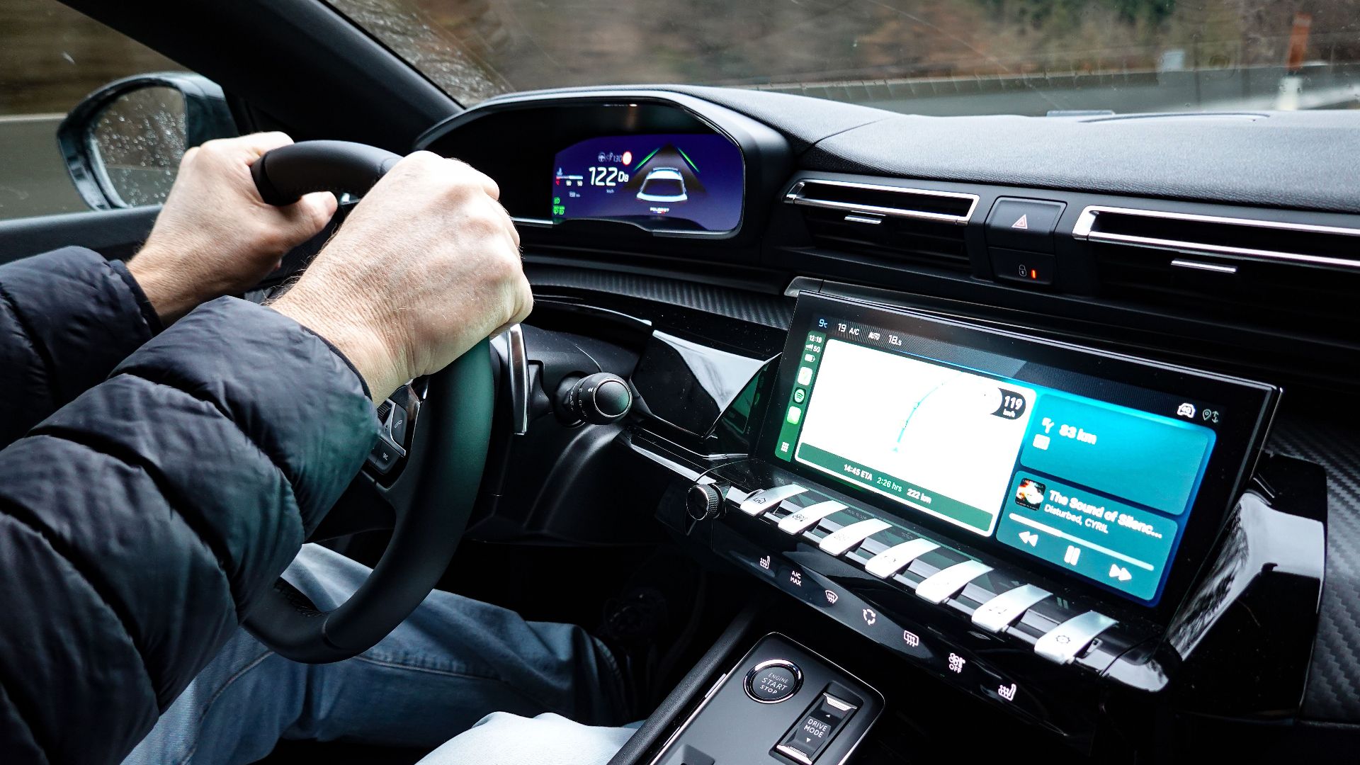 A detailed view of a car's interior with hands on the steering wheel, showcasing modern technology.