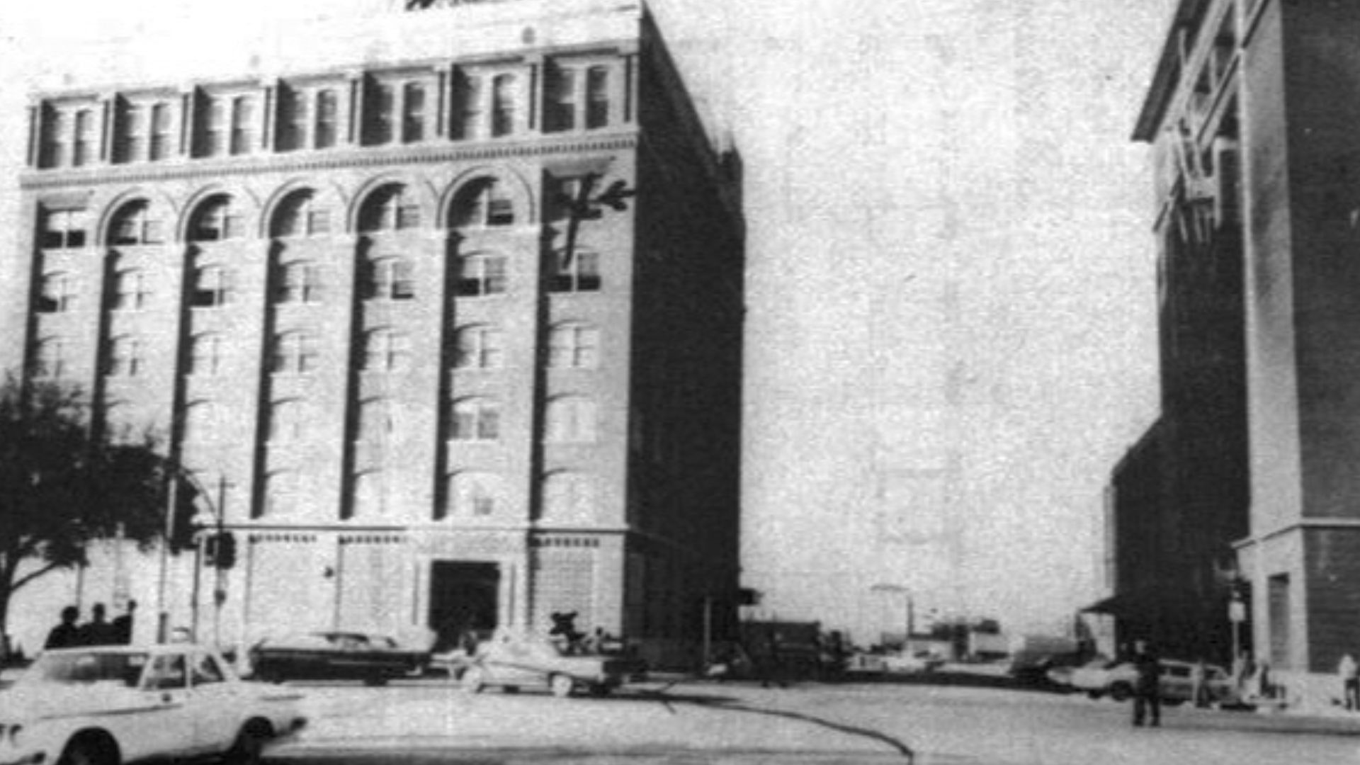 Texas School Book Depository from Houston Street. Mark on 6th floor. Originated from the report of the Warren Commission, a US Government report, WH Vol.16 p.957.