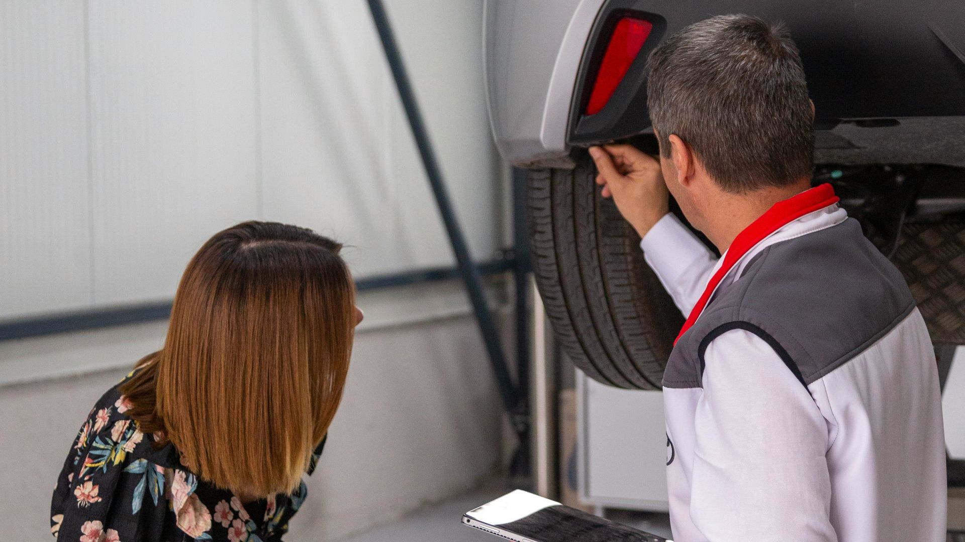 A man and a woman looking under a car