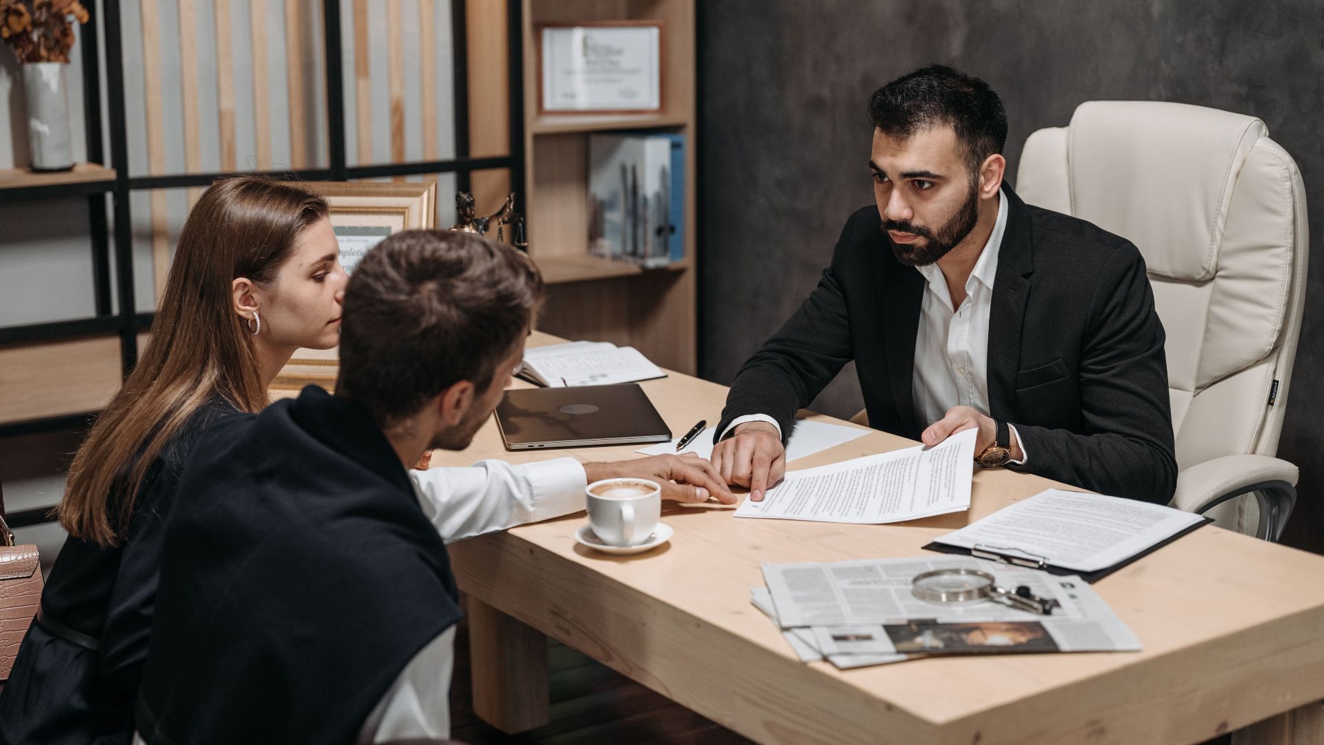 Lawyer discussing legal documents with clients at office desk.