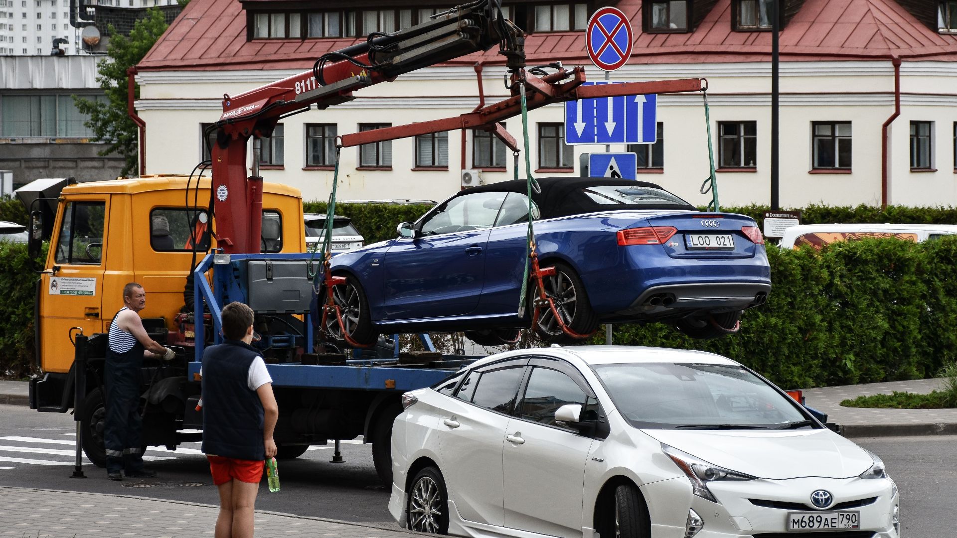 Towing a blue Audi convertible in a bustling city street.