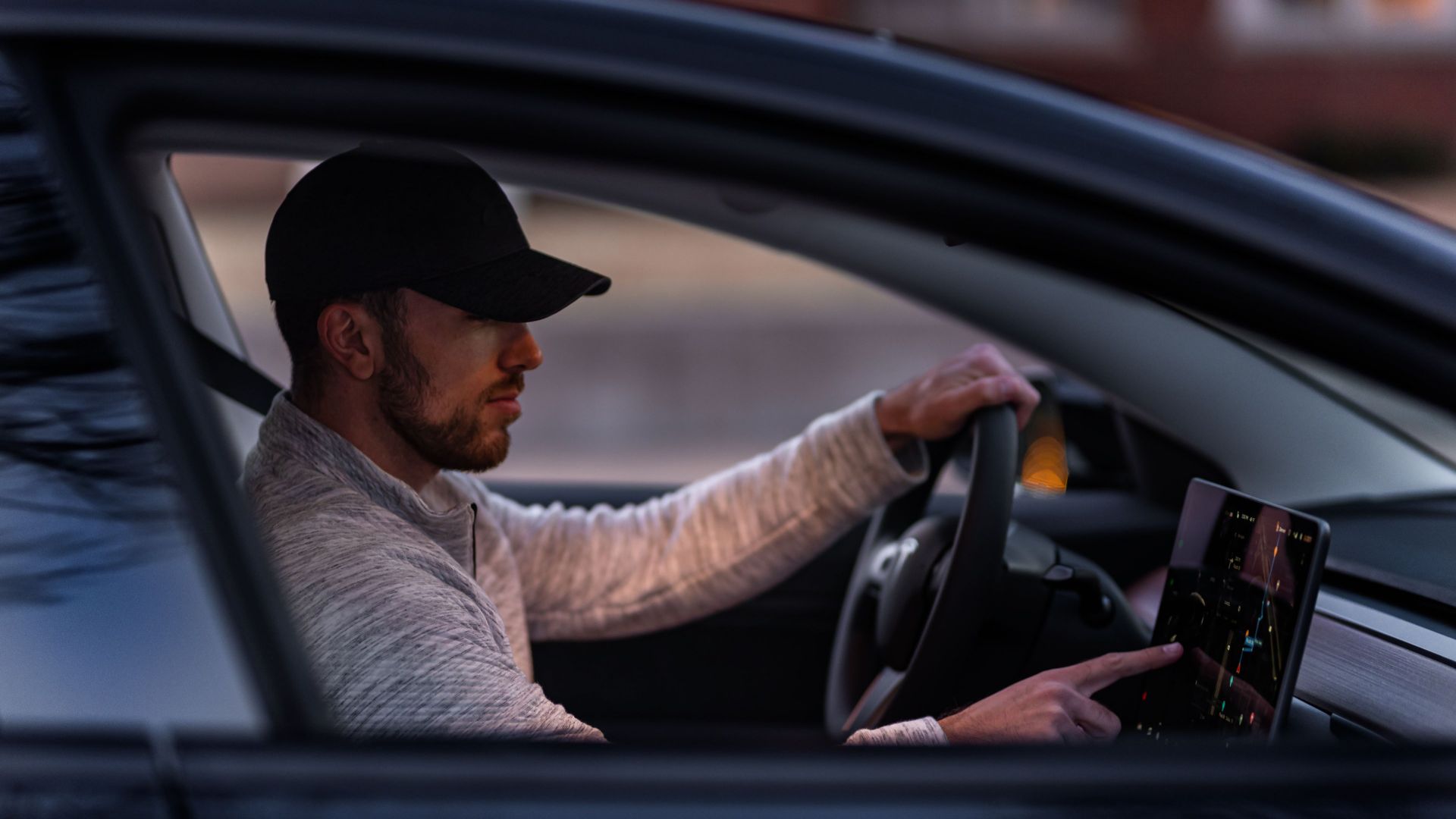 A man interacts with a touchscreen inside an electric car, driving through Dallas, TX.