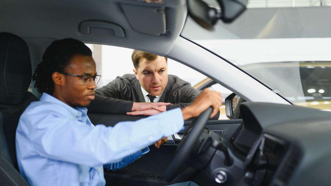 Shutterstock - 2683893331 - Male car dealer having conversation with pensive young man client at showroom. Man listening manager while buying car at dealership center.