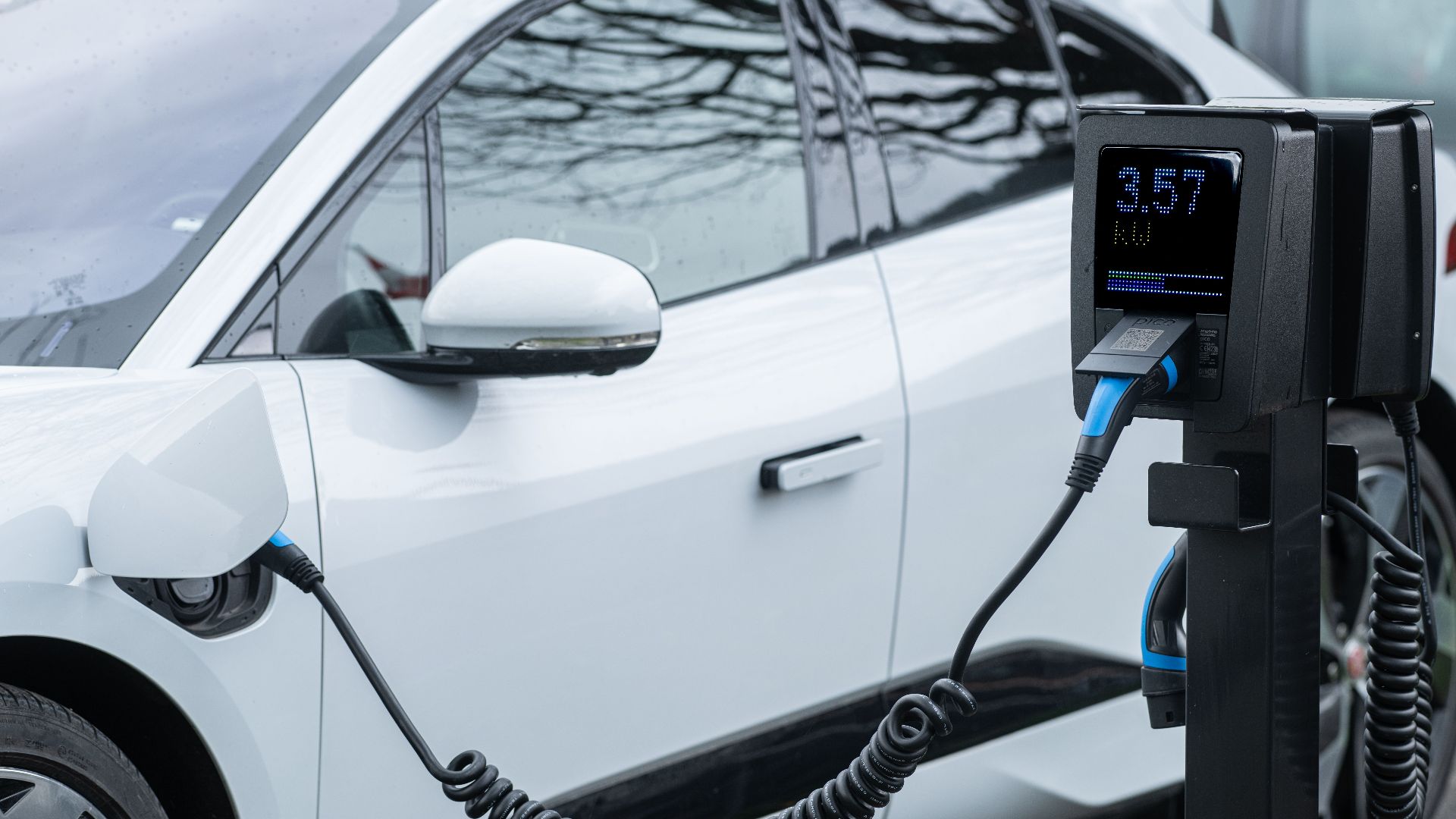 Close-up of an electric vehicle charging at a station, showcasing energy-efficient technology.