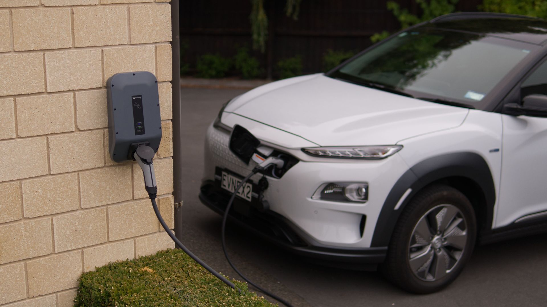 A white electric car charging at a station in Christchurch, New Zealand, showcasing modern eco-friendly transportation.