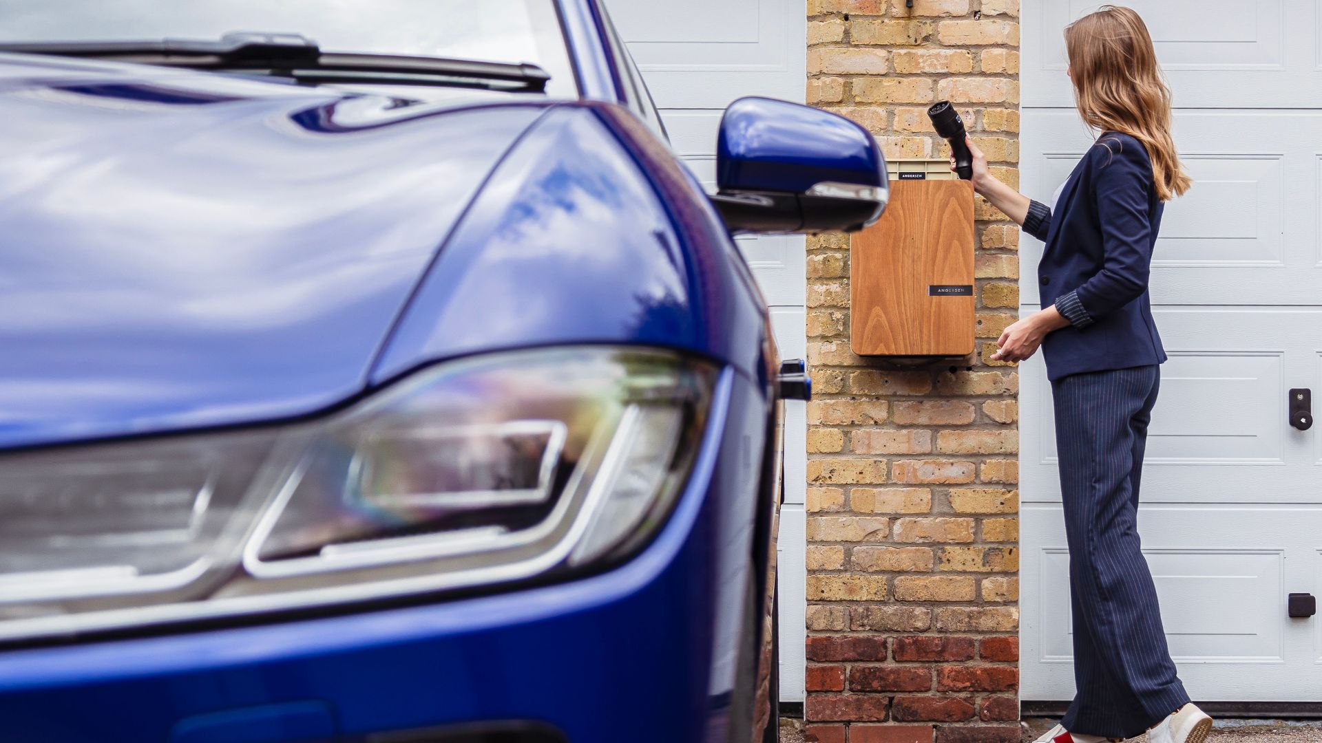 Woman charging an electric car at a home station, promoting sustainability.