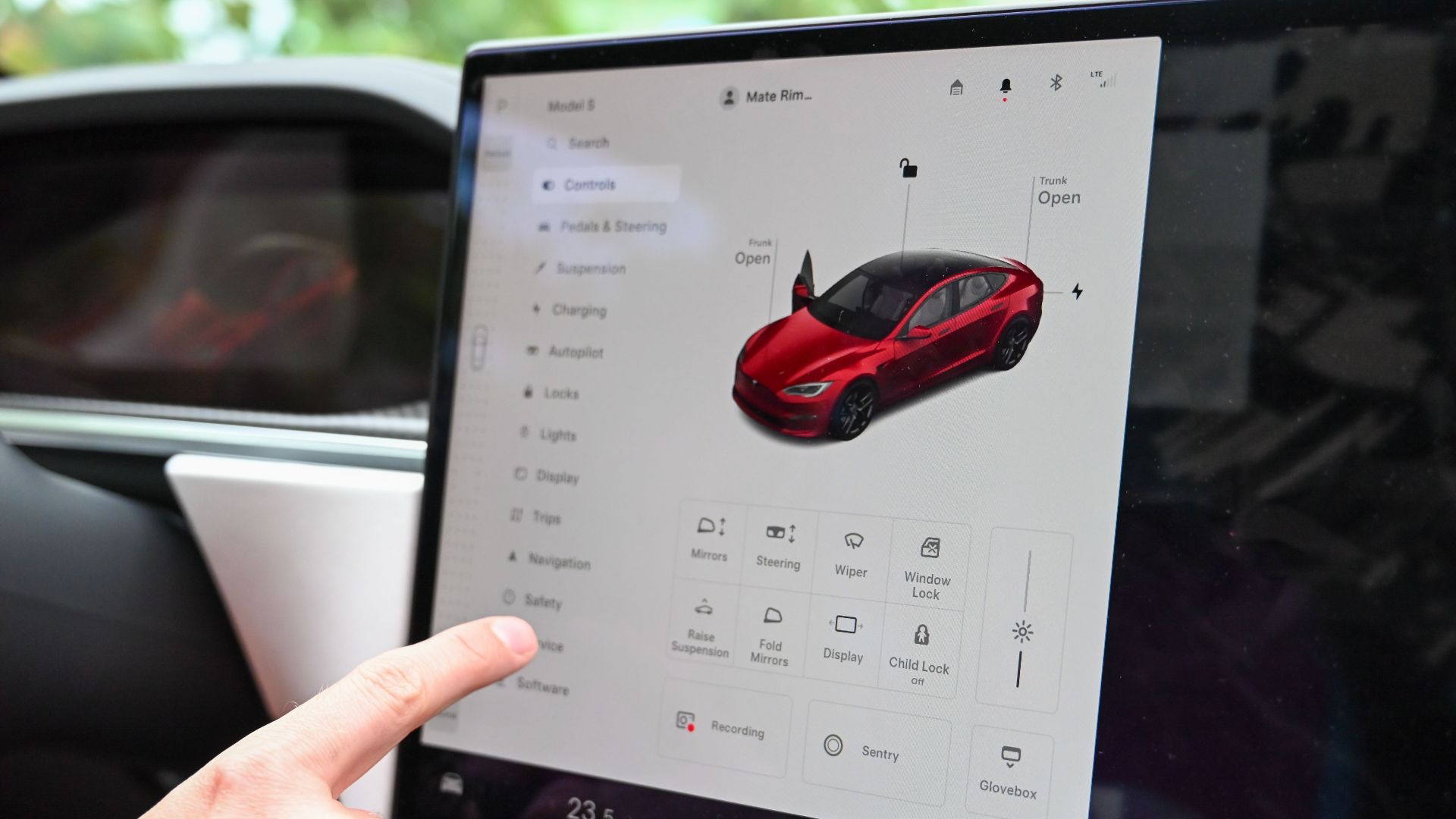 Close-up of a hand interacting with a modern car's touchscreen interface for various controls.