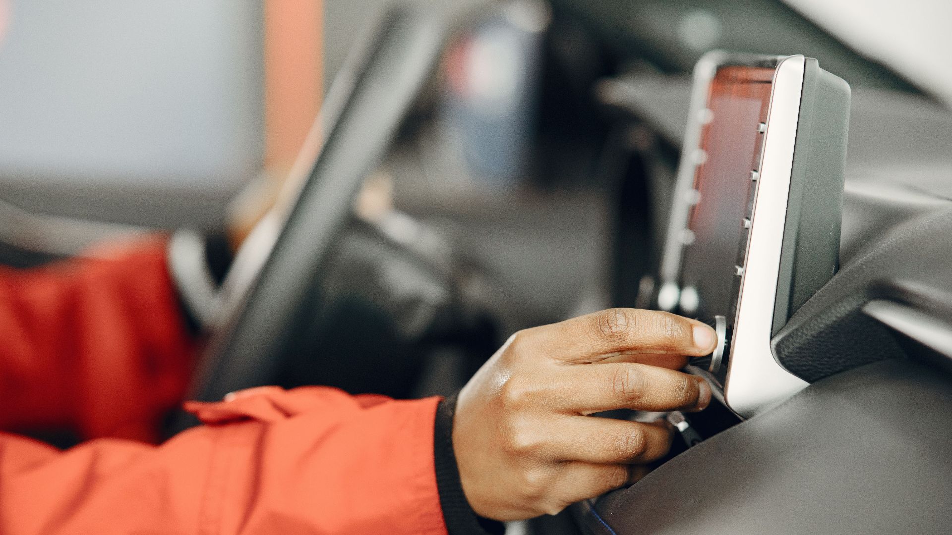 Close-up of a hand adjusting the car stereo while driving, highlighting technology and focus.