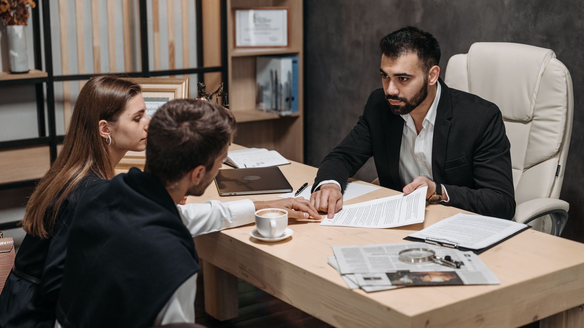 Lawyer discussing legal documents with clients at office desk.