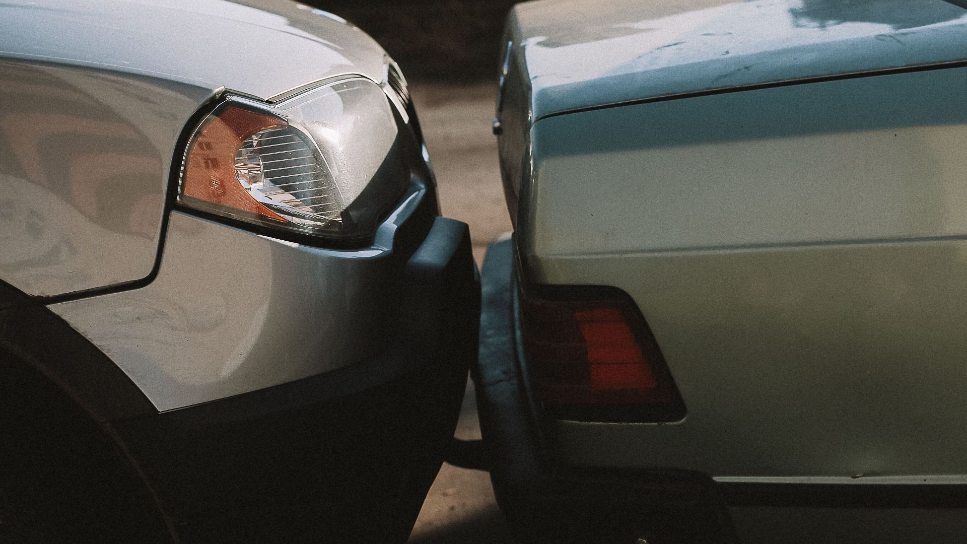 A close-up view showing the aftermath of a rear-end car collision in an outdoor setting.