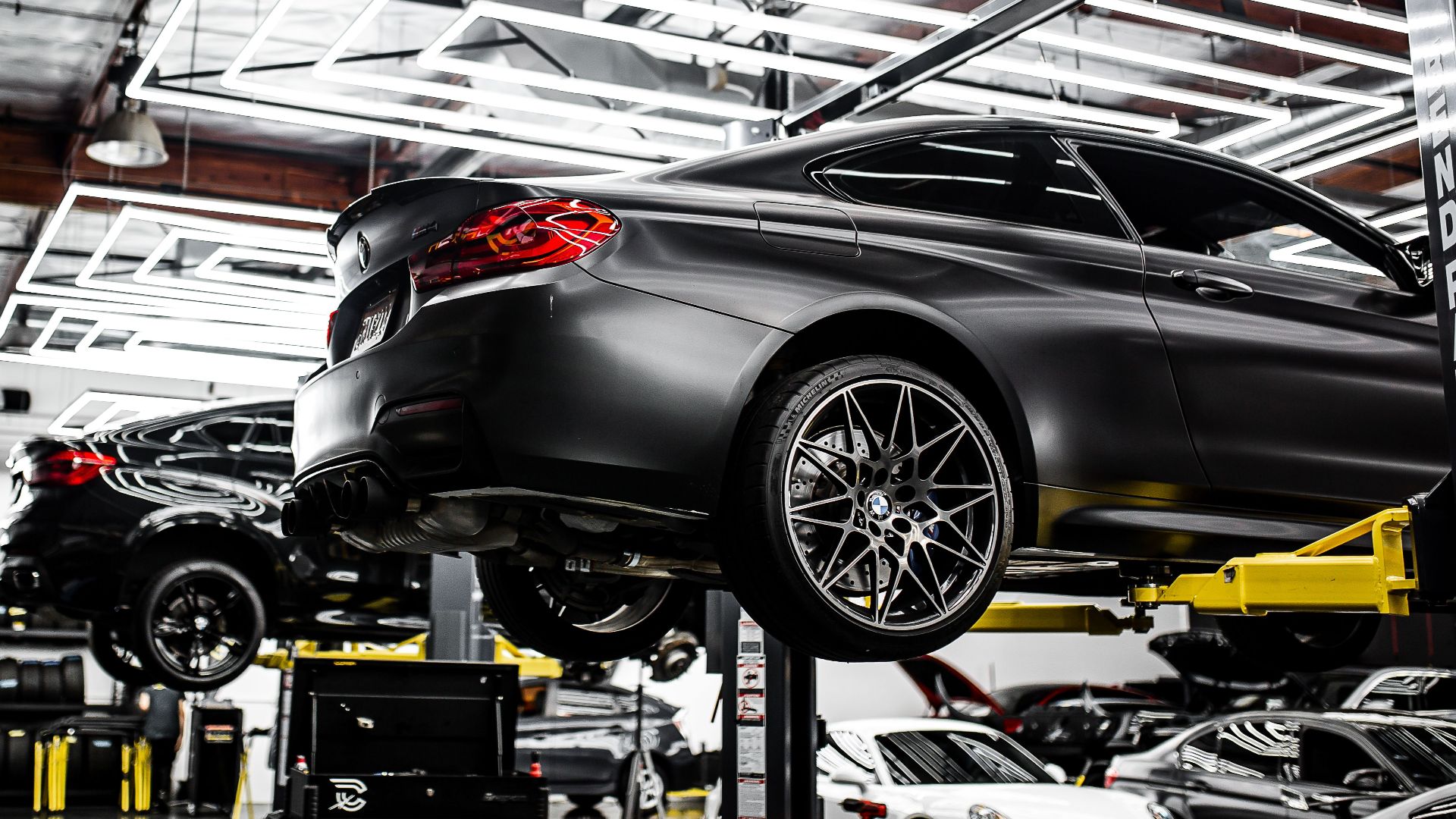 A modern car repair shop showcasing vehicles on lifts and a well-lit, organized interior.