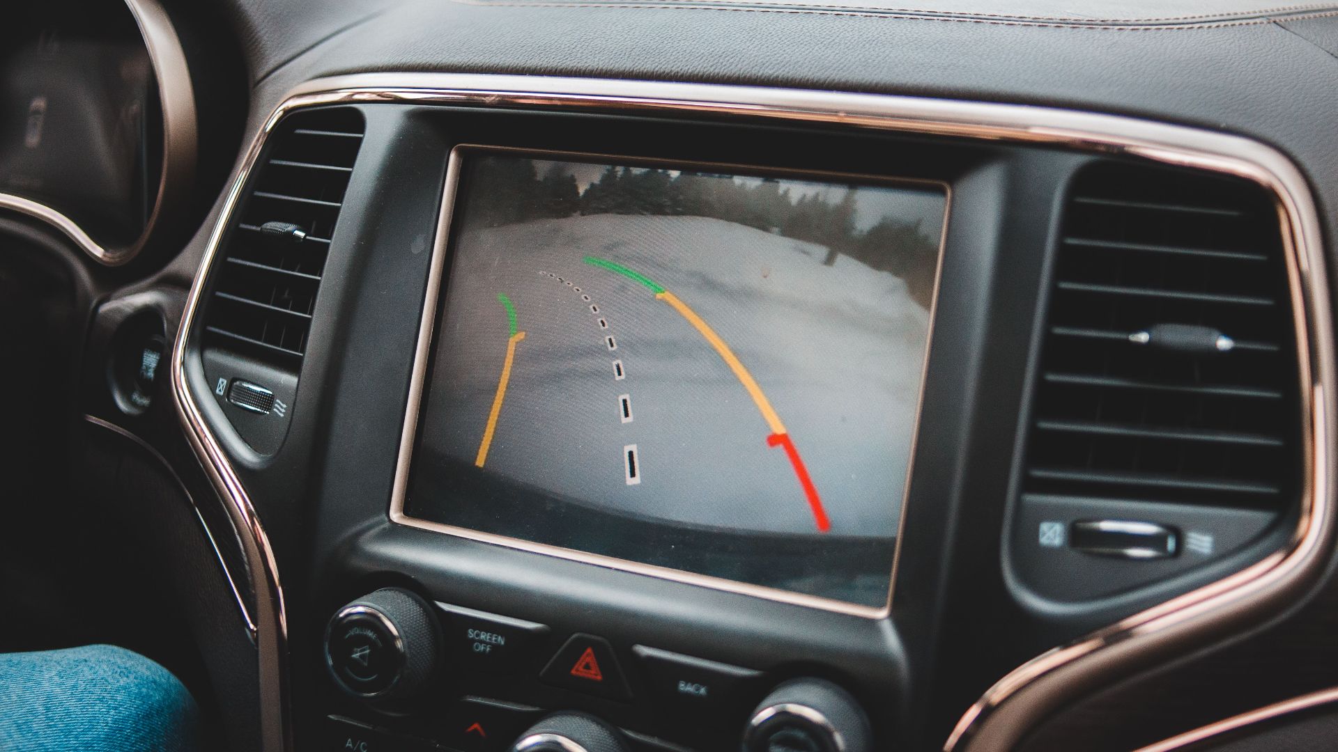 Close-up of a car's dashboard showing a rearview camera display for parking assistance.