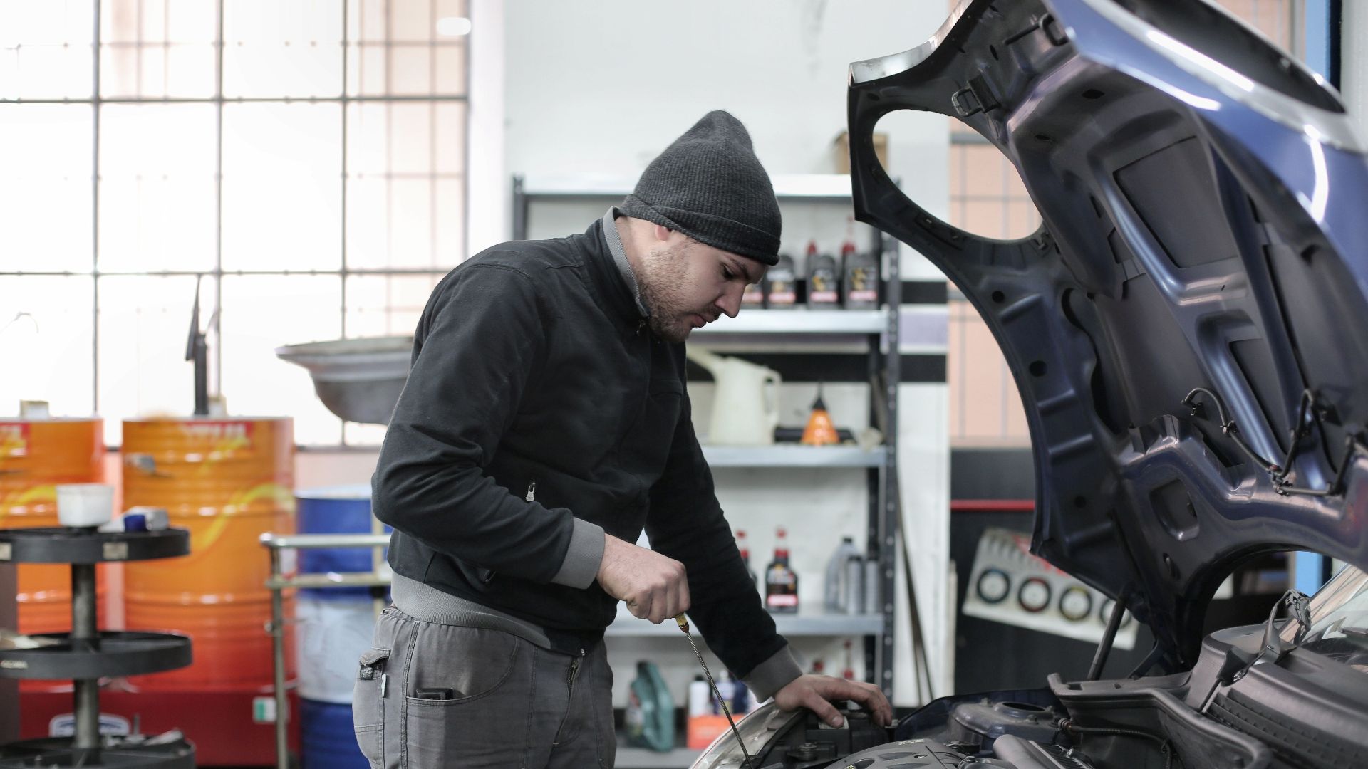 Mechanic checking a car engine in a garage, ensuring quality maintenance and repair.