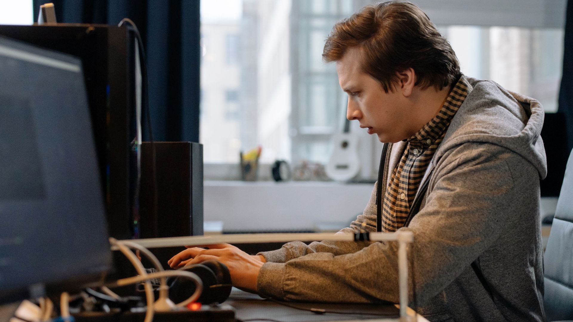 A concentrated professional working at a computer in a modern office setting.