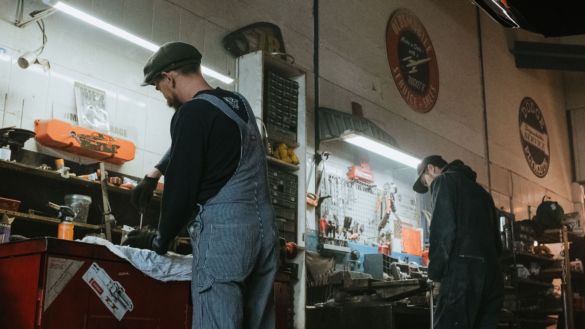 Two mechanics in a garage working on vehicle repair and maintenance.