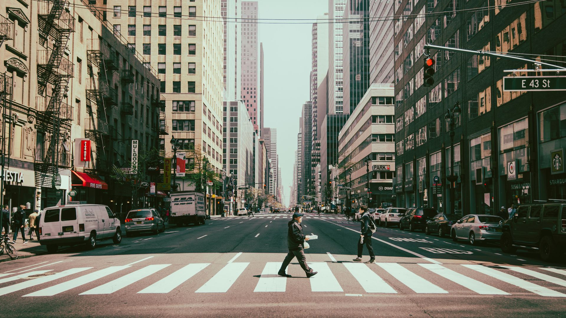 man in black jacket and pants walking on pedestrian lane during daytime