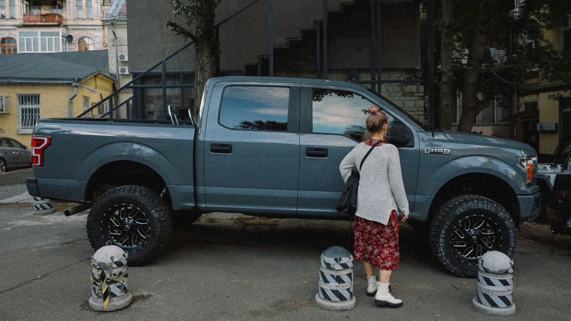 man in white shirt standing beside gray crew cab pickup truck during daytime