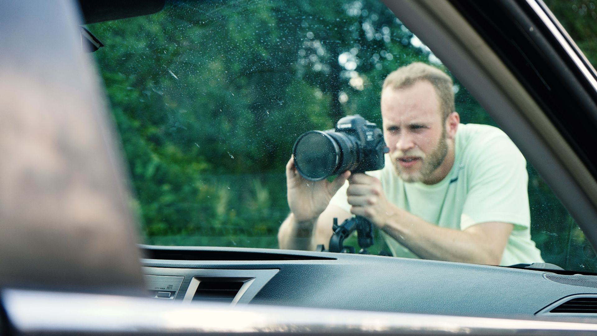 Photographer focusing on details through a car window on a sunny day.