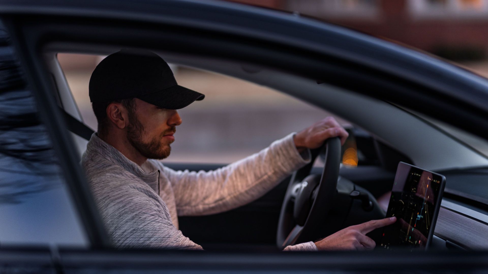 A man interacts with a touchscreen inside an electric car, driving through Dallas, TX.