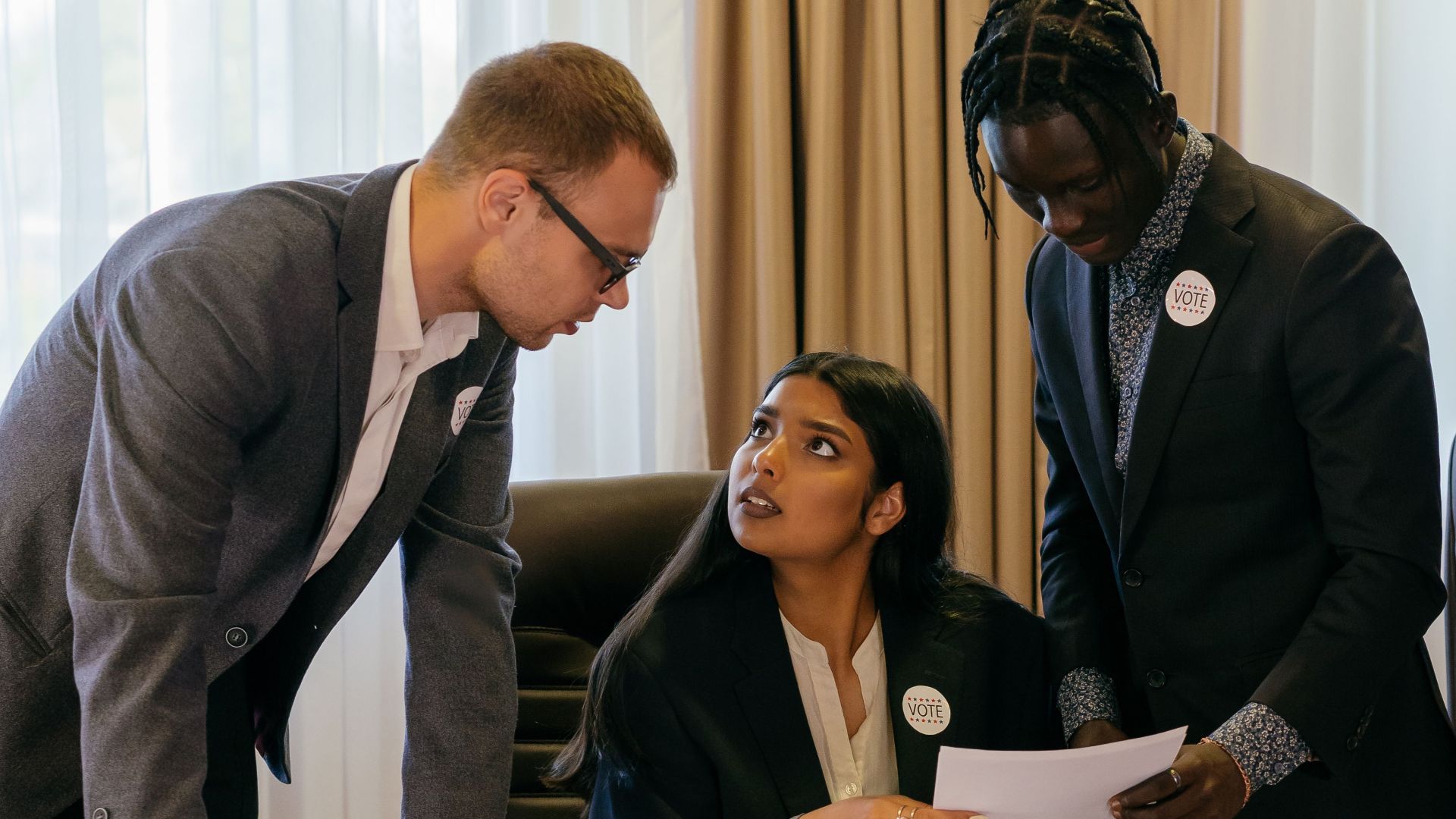 Three diverse professionals collaborate seriously in a meeting room, discussing important documents.