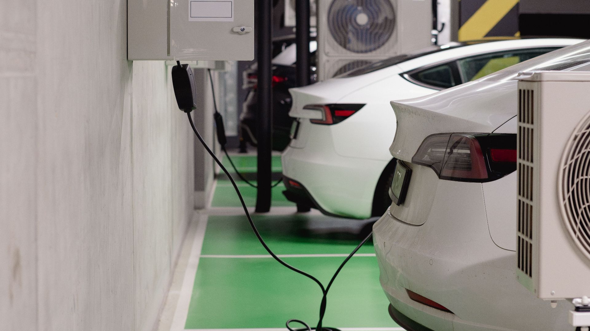 Electric vehicles charging at an indoor station in a modern underground garage.