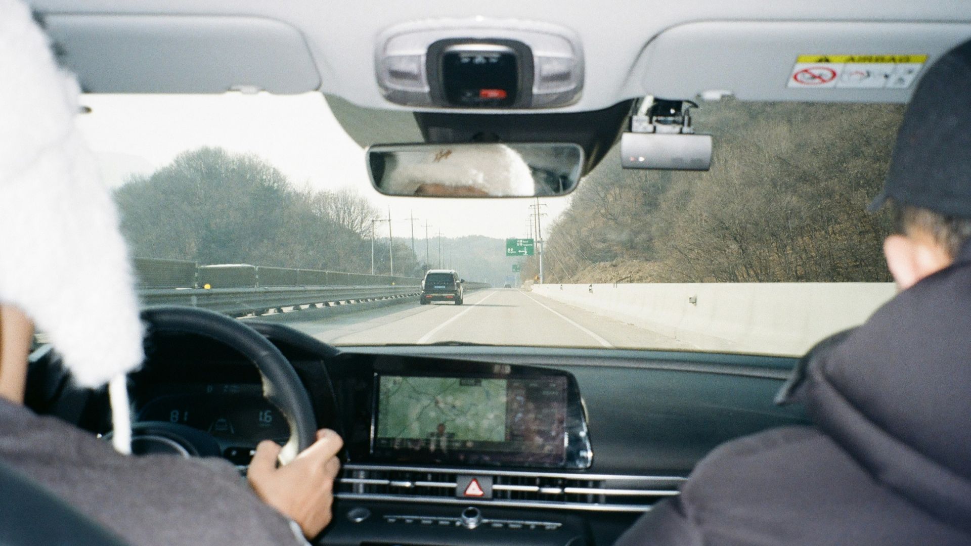 Two people driving a car on a highway