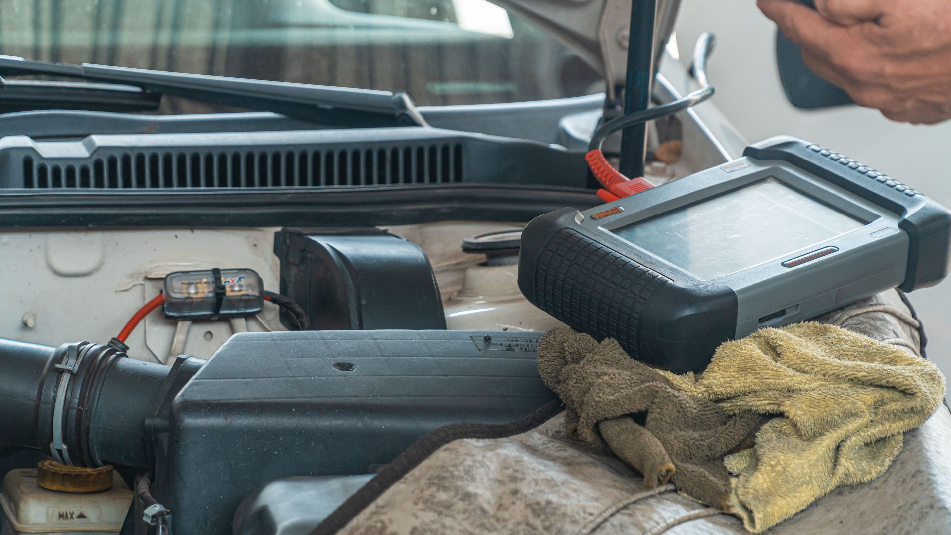 Close-up of a car engine inspection using a diagnostic tool in a garage setting, showcasing automotive maintenance and repair.