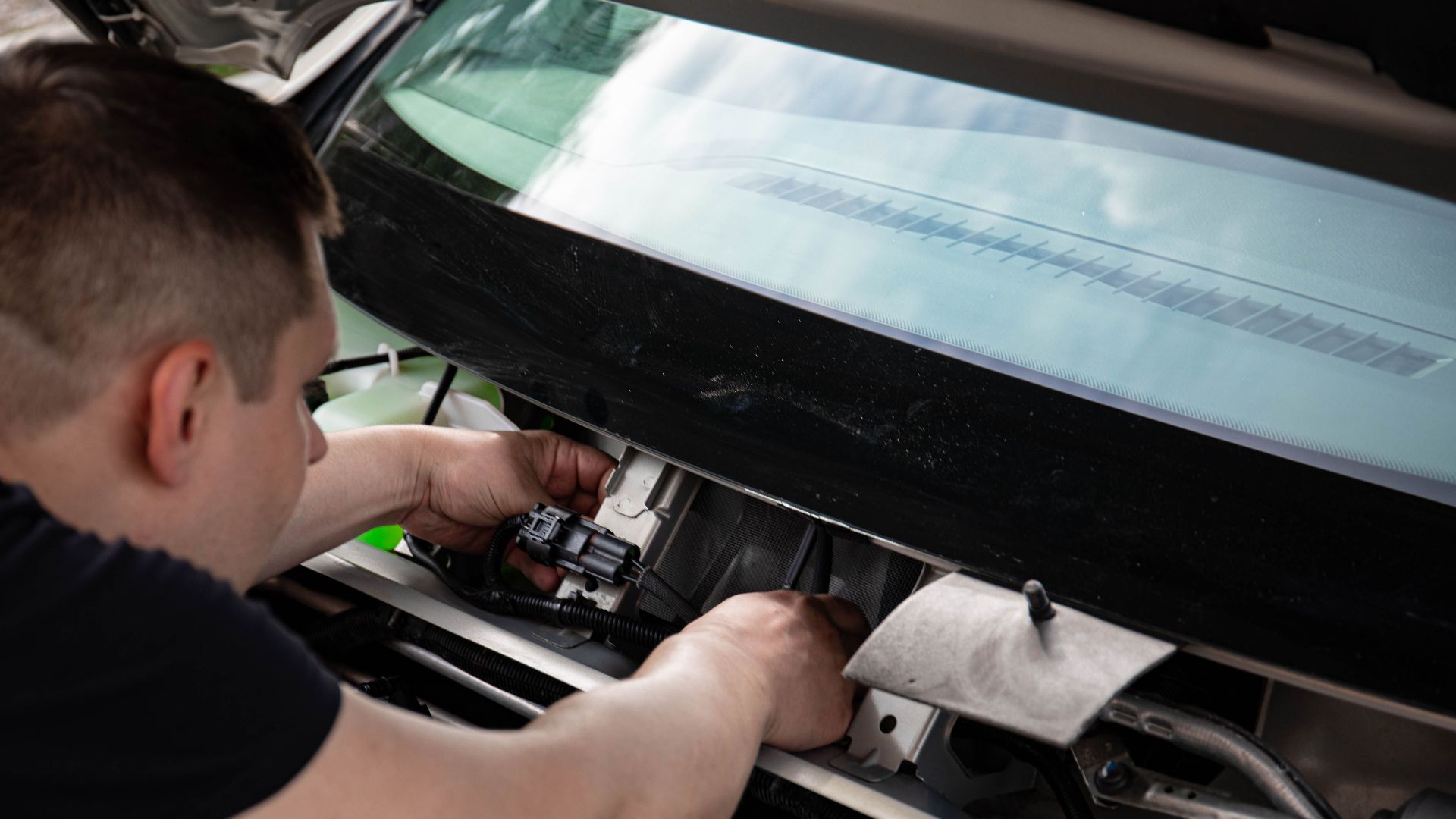 A mechanic working on car engine repairs inside a workshop setting.