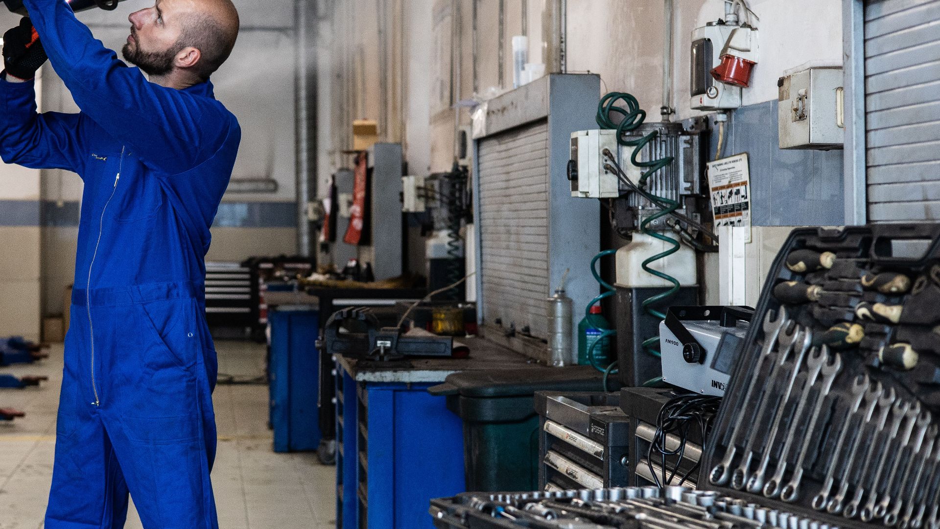 Mechanic inspecting a raised car in an auto workshop for maintenance and repair services.