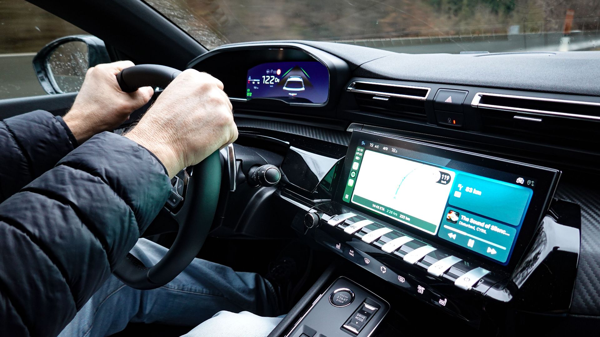 A detailed view of a car's interior with hands on the steering wheel, showcasing modern technology.