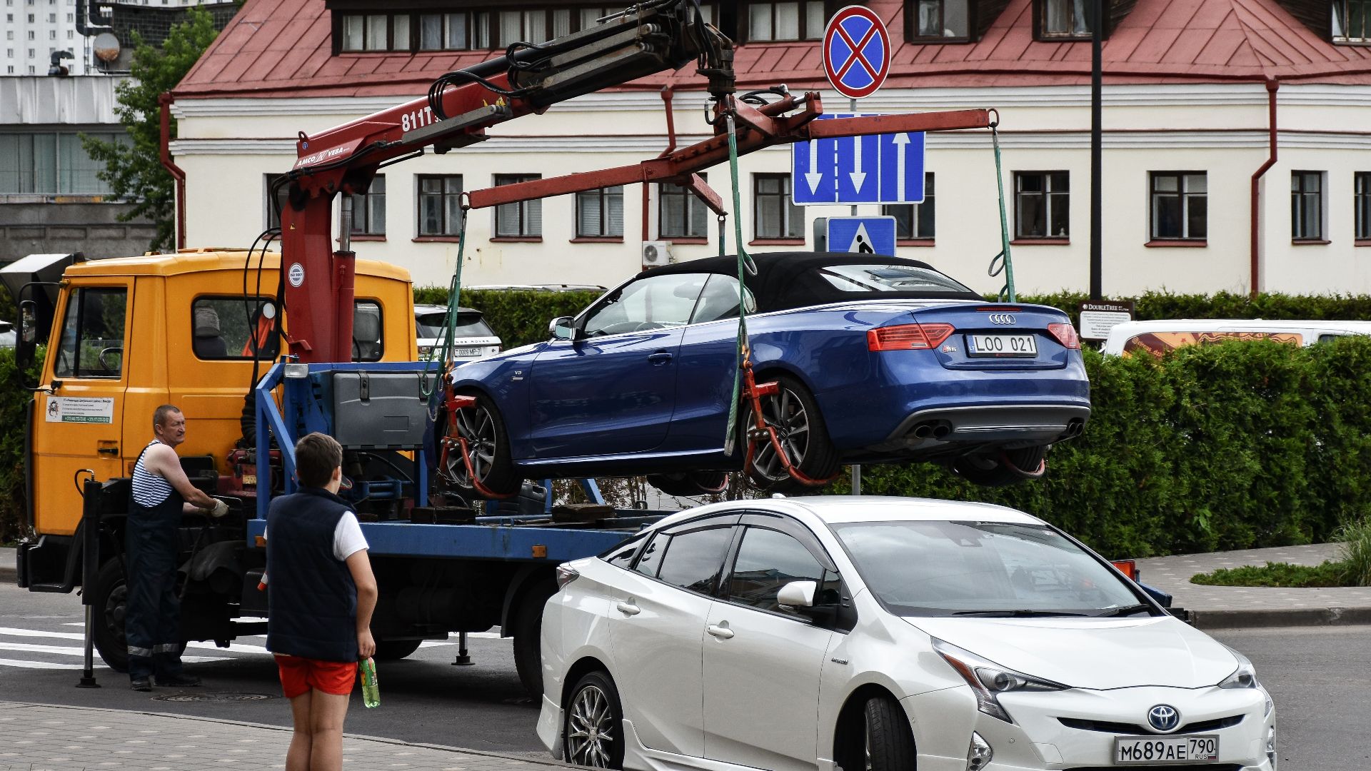 Towing a blue Audi convertible in a bustling city street.