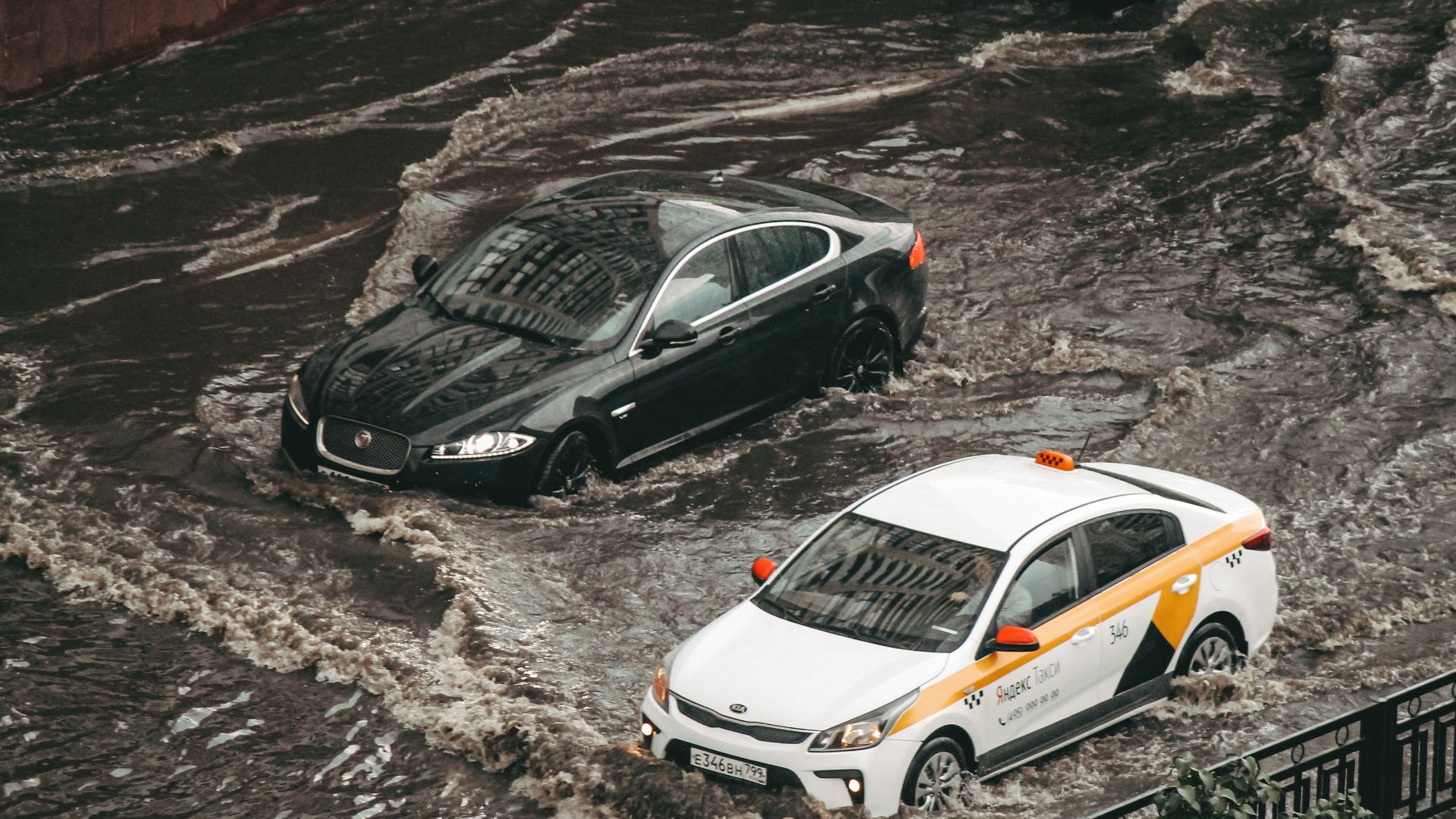 Cars navigating through a flooded city street, showcasing urban chaos and weather impacts.